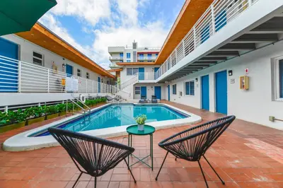 a pool in the courtyard of a building with two chairs at Beachfront Getaway Studio with Parking - M21 in Hollywood