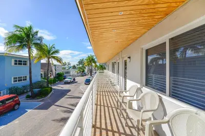 a balcony with white chairs and palm trees on a street at Family Friendly Beach Escape with pool and parking - M41 in Hollywood
