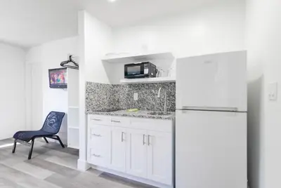 a white kitchen with a refrigerator and a chair at Spacious Oceanfront Studio with pool access - M27 in Hollywood