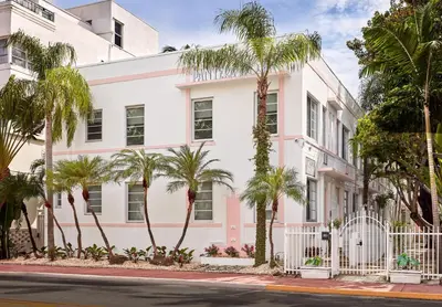 a white building with palm trees in front of a street at Pantera Rosa in Miami Beach