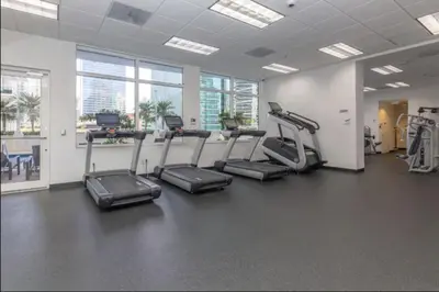 a gym with treadles and ellipticals in a room with windows at Iconic Sunset Views with Pool, Hot tub, GYM, and Parking in Miami