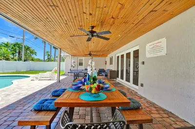 a wooden table on a patio next to a pool at Spectacular 5BR & 5BA Villa in Hollywood Lakes in Hollywood