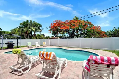 a swimming pool with two lawn chairs and a table and two at Spectacular 5BR & 5BA Villa in Hollywood Lakes in Hollywood