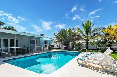 a swimming pool with chairs and a house at Luxury 5BR Villa Heated Pool near Beach & Casino in Dania Beach