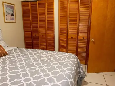 a bedroom with a bed and some wooden cabinets at Pool home in Miami in Tamiami