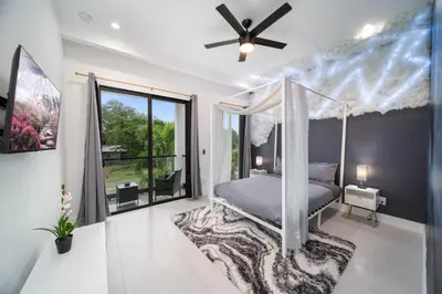 a bedroom with a canopy bed and a large window at The Elements Luxury Home Fort Lauderdale in Fort Lauderdale