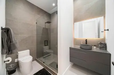 a bathroom with a toilet and a sink and a mirror at The Elements Luxury Home Fort Lauderdale in Fort Lauderdale
