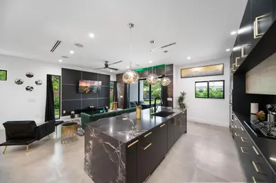 a kitchen with black cabinets and a living room at The Elements Luxury Home Fort Lauderdale in Fort Lauderdale