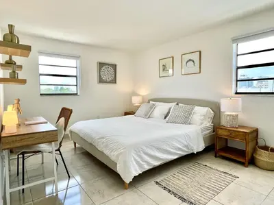 a bedroom with a bed and a desk and two windows at Large 1 bedroom apartment with free private parking in Miami Beach