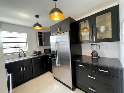 a kitchen with black cabinets and a stainless steel refrigerator at Large 1 bedroom apartment with free private parking in Miami Beach