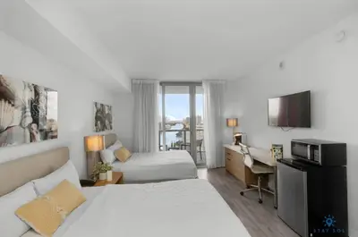 a hotel room with two beds and a desk at Infinite View with Balcony, Amazing Pool, Gym in Hallandale Beach