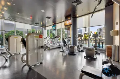 a gym with cardio equipment in a building with windows at Infinite View, Balcony with Gym and Amazing Pool in Hallandale Beach