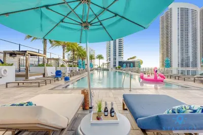 a pool with a blue umbrella and chairs and a pool at Wrap Around Balcony, Insane Amenities, Amazing Pool in Hollywood