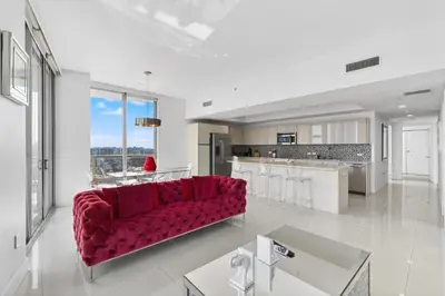 a living room with a red couch and a kitchen at Spacious VIP Penthouse with Ocean & Intracoastal Views, Private Entry, Resort Amenities in Hallandale Beach