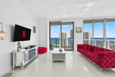 a living room with a red couch and a tv at Spacious VIP Penthouse with Ocean & Intracoastal Views, Private Entry, Resort Amenities in Hallandale Beach
