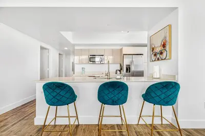 a kitchen with two blue chairs at a counter at Beachwalk Resort - PENTHOUSE IN THE SKY 3BDR and 3BA LUXURY CONDO DIRECT OCEAN VIEW in Hallandale Beach