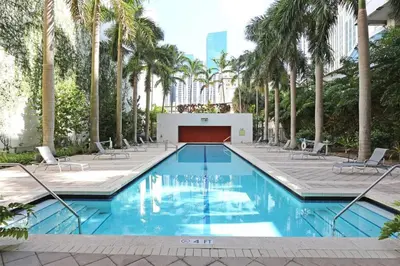 a swimming pool with chairs and palm trees at Center Stage- Downtown Parking Pool Hot Tub in Miami
