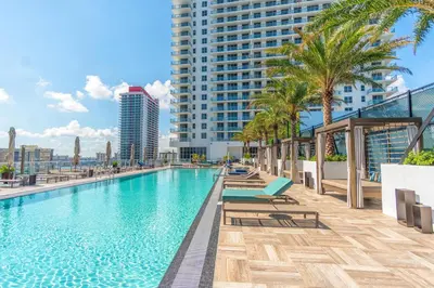 a swimming pool with chairs and palm trees on a building at Hyde Beach House 2309 in Hollywood