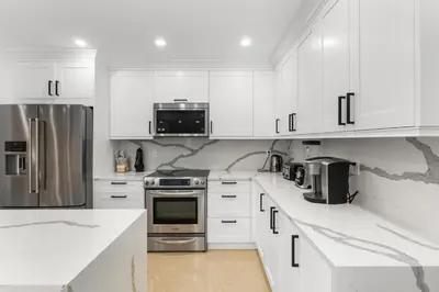 a kitchen with white cabinets and stainless steel appliances at Spacious Modern Mansion w Pool & Sauna in Hollywood close to Beach in Hollywood