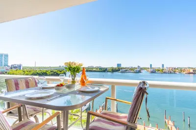 a table on a balcony with a view of the water at Golden Bay 703 in Miami Beach