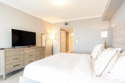 a white bedroom with a large bed and a flat screen tv at Golden Bay 808 in Miami Beach