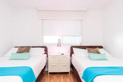 two beds in a bedroom with white walls and blue pillows at Golden Bay 805 in Miami Beach