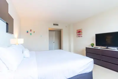 a bedroom with a white bed and a flat screen tv at Ocean Reserve 1404 in Miami Beach