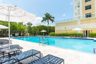 a swimming pool with chairs and umbrellas next to a building at Golden Bay 402 in Miami Beach
