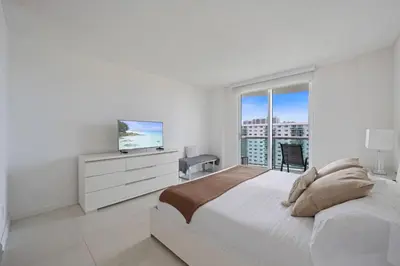 a white bedroom with a large bed and a television at Ocean Reserve 1616 in Miami Beach