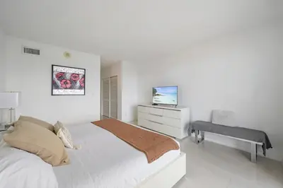a white bedroom with a bed and a desk at Ocean Reserve 1616 in Miami Beach