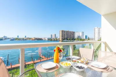 a table with food on a balcony with a view of the water at Golden Bay 508 in Miami Beach