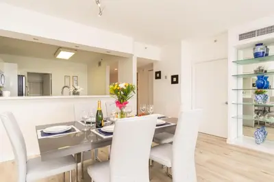 a dining room with a table and white chairs at Golden Bay 1003 in Miami Beach