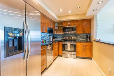 a kitchen with wooden cabinets and a stainless steel refrigerator at Ocean Reserve 1515 in Miami Beach