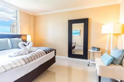 a bedroom with a bed and a chair and a mirror at Ocean Reserve 1515 in Miami Beach