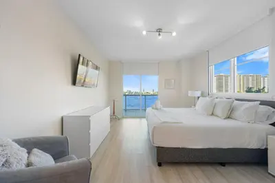 a white bedroom with a large bed and a chair at Golden Bay 509 in Miami Beach