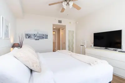 a white bedroom with a white bed and a flat screen tv at Golden Bay 602 in Miami Beach