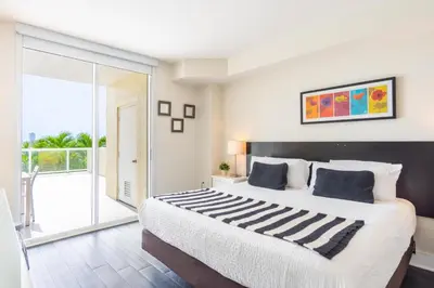 a bedroom with a large bed and a balcony at Golden Bay 302 in Miami Beach