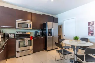 a kitchen with stainless steel appliances and a table with chairs at Golden Bay 303 in Miami Beach