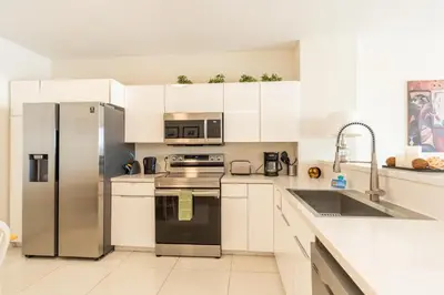 a kitchen with white cabinets and a stainless steel refrigerator at Golden Bay 707 in Miami Beach