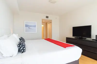 a bedroom with a white bed and a flat screen tv at Golden Bay 707 in Miami Beach