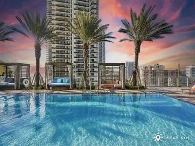 a large swimming pool with palm trees on a building at Beachfront Condo Front Oceanview Balcony Pools in Hollywood