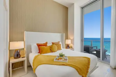 a bedroom with a bed with a view of the ocean at Beachfront Condo Front Oceanview Balcony Pools in Hollywood
