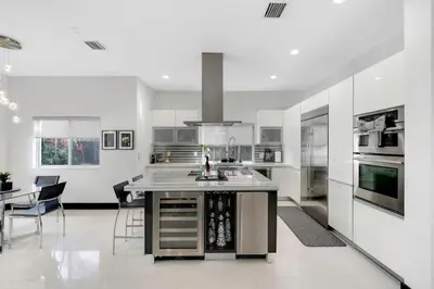 a white kitchen with a island in the middle at Luxury home w pool by PMI in Miami