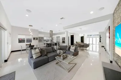 a living room with a gray couch and a kitchen at Luxury home w pool by PMI in Miami