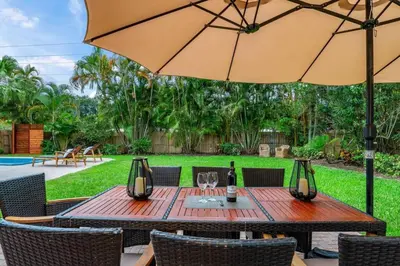 a wooden table with an umbrella in a yard at Fox Private Resort-Heated Pool, Spa-Downtown&Beach in Fort Lauderdale