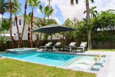 a pool with chairs and an umbrella next to a yard at Fox Private Resort-Heated Pool, Spa-Downtown&Beach in Fort Lauderdale