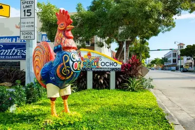 a colorful chicken statue sitting in the grass next to a sign at Private Rooms close to Miami Airport - Free parking - 02 in Miami
