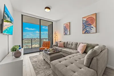 a living room with a couch and a large window at Devereaux Miami 2 Bedroom, 1 Bedroom, and Studio Condos with Balconies in Miami