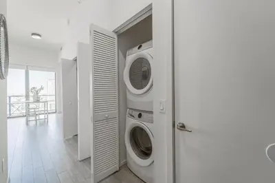 a white laundry room with a washer and dryer at Devereaux Miami 2 Bedroom, 1 Bedroom, and Studio Condos with Balconies in Miami