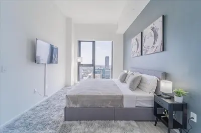 a white bedroom with a large bed and a tv at Devereaux Miami 2 Bedroom, 1 Bedroom, and Studio Condos with Balconies in Miami